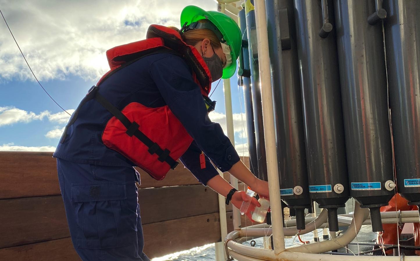 Lt. j.g. Edmonds is on the left collecting water samples from a CTD device on the right.