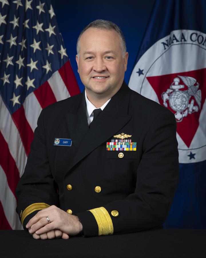 Rear Admiral Chad Cary with U.S. and NOAA Corps flags behind him